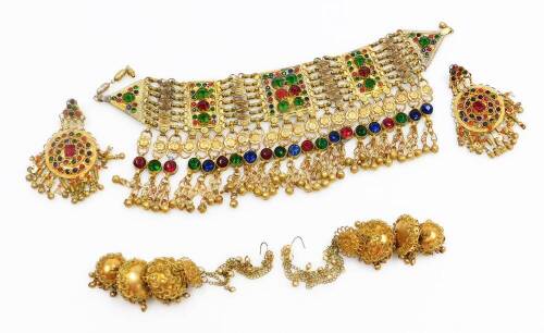 Eastern dress jewellery, to include a brass multi row set choker, with rectangular panels and drop tassels with bells, with matching clip on earrings, a pair of three tiered Indian filigree patterned brass clip on earrings. (3)