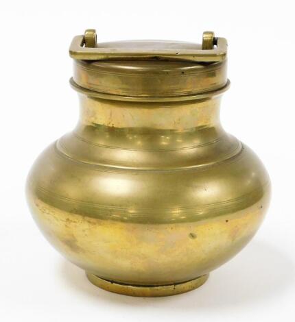 A brass storage canister, the circular fixed top with square handle, on a baluster body with a circular foot, silver coloured to underside, 18cm high.