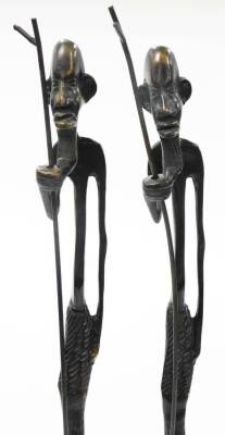 A pair of African bronze tribal sculptures, each of an elongated man with beard and walking stick, on a square tapered base, 66cm high, 6cm wide. (2) - 2