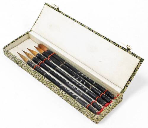 A cased calligraphy set, with five Chinese calligraphy brushes in a green storage box.