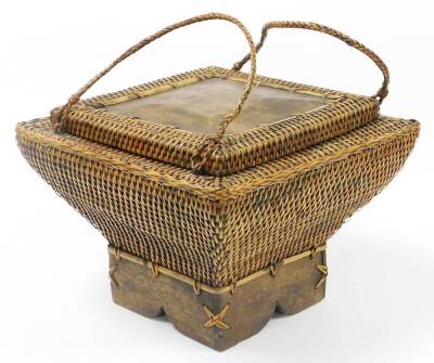 An Eastern wicker storage basket, shaped rectangular form, on a wooden base, with two carrying handles and lift up lid, 34cm high, 42cm wide.