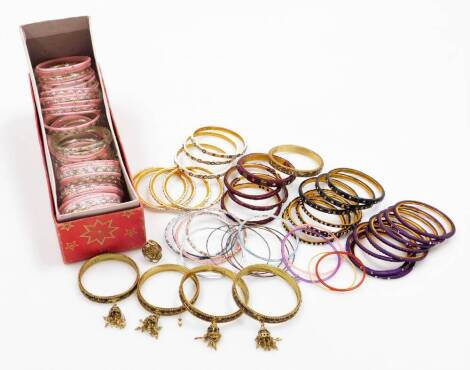 Various dress bangles, of varying design and colour, to include pink examples, clear beaded purple, and four gold coloured cabochon stone set bangles. (a quantity)