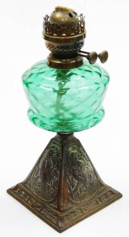 A Victorian aesthetic oil lamp base, the green glass reservoir on a square tapered metal base with panels of birds and flowers, 38cm high.