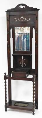 An oak hall stand, with pierced pediment top, mirrored central back plate, six metal hooks, a cupboard section, on a cane/umbrella stand base, with barley twist columns, 190cm high, 60cm wide, 30cm deep.