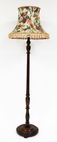 An oak standard lamp, with floral shade, on a part fluted stem, on a circular layered base, 70cm high.