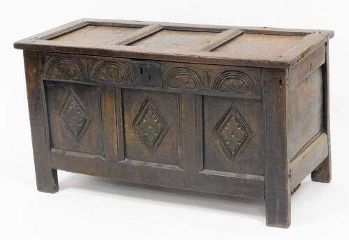 A late 17th/early 18thC oak coffer, the three panelled top section with metal hinges, on a carved two panel front with shield crest and sundial type decoration with a metal lock panel, 59cm high, 107cm wide, 50cm deep.