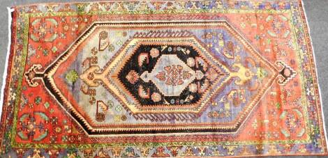 A Hamadan design Iranian carpet, with central black medallion, depicting symbols and flowers, on a Greek key border, 256cm x 133cm, bearing label and No 2502 to back.