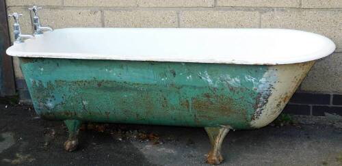 A Victorian cast iron and enamel bath, of bull nose shape on heavy cast hairy paw feet, with two taps and plug, 160cm long.