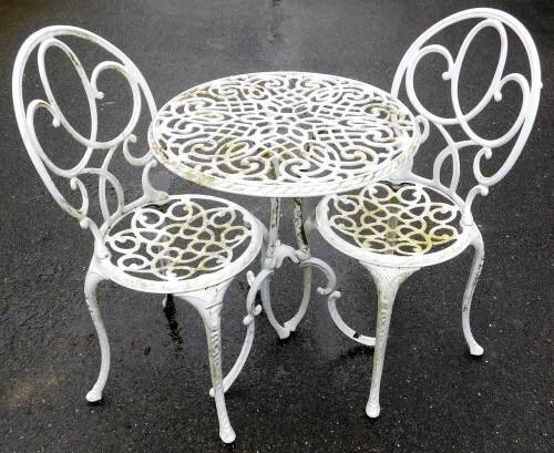 A two seater cast alloy garden bistro set, the circular seats and table with pierced decoration, in white. (3)