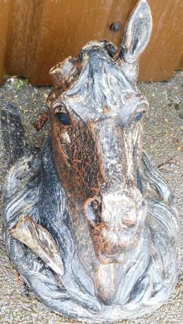 A concrete wall mounted horse's head garden ornament, later painted in brown and black, one ear broken, 45cm high, 30cm deep.