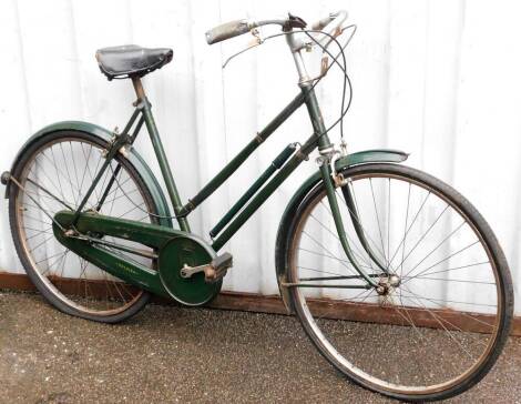 A Sturmey Archer geared vintage ladies bicycle, with a green frame on a black leather seat.