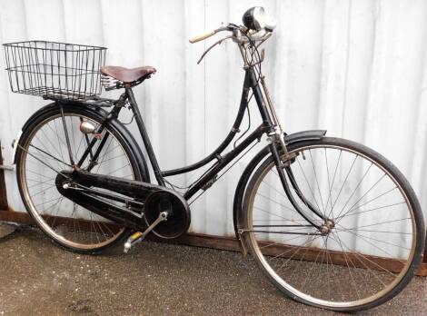 A Sturmey Archer geared vintage ladies bicycle, with a front bicycle lamp, Miller's bike bell and a Brookes brown leather seat, and a grocery basket.