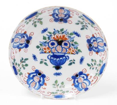 An 18thC Dutch Delft plate, with painted decoration of flowers in blue, red and green, 22cm diameter. (AF)