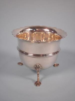 An Edwardian silver sugar bowl with a shaped legs with pad feet