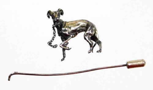 A late 20thC greyhound stick pin, the top with a silver coloured greyhound with red cabochon eyes, on a silver plated pin (AF), 9cm high.