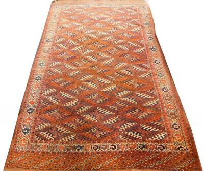 A Tekke Turkoman type carpet, with a lozenge design in blue and red, on a brown ground with one wide and one narrow border, 233cm x 200cm.