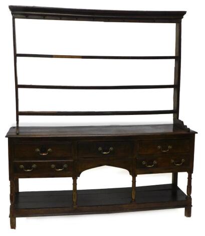 A late 18th/early 19thC oak dresser, the associated raised back with three plate shelves, the base with a moulded edge above an arrangement of five drawers around an arch, on turned supports with pot board and stiles, 200cm high, 177cm wide, 45cm deep.