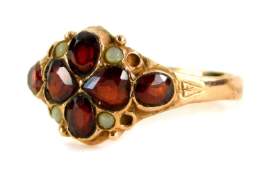 A 9ct gold garnet dress ring, the central four leaf clover design garnet with four moonstone borders and two oval cut amethyst sides, with shield engraved shoulders, ring size P, 2.5g all in.