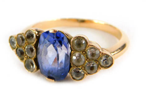 An Art Deco style ring, with oval cut pale blue sapphire, flanked by triangle staggered design set with six white sapphires, on a yellow metal band, unmarked, ring size J, 4.1g all in.