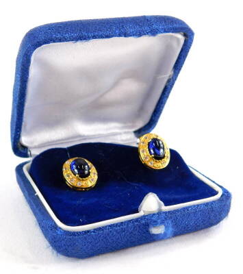 A pair of sapphire and diamond earrings, each with central cabochon cut sapphire in four claw setting, surrounded by tiny diamonds, yellow metal, on butterfly backs, marked 585, earring 1.5cm wide, 3.6g all in.