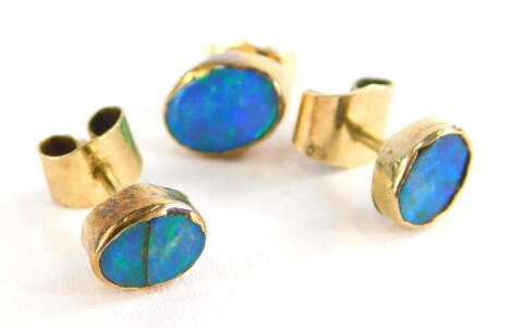 Three various opal set earrings, each set with oval cut opals in rub over setting, each with butterfly backs, yellow metal, unmarked, 1.9g all in.