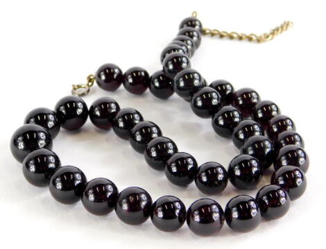 A garnet necklace, with graduated spherical beads, the largest 1cm wide, the smallest 8mm wide, on clear string, with silver clasp, 44cm long overall.