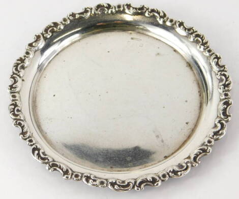 A silver card tray or waiter, the border cast with scrolls, etc., indistinctly hallmarked, 5½oz, 19cm diameter.