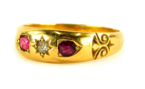 An Edwardian 18ct gold dress ring, set with central star set diamond and two rubies, with scroll design shoulders, ring size S, Birmingham 1907, 3.4g all in.