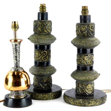 A pair of Indian brass table lamps, each modelled with scrolls, 'S' shaped motifs, and applied with bangles, 41cm high overall, and an Indian copper and silvered metal table lamp, 34cm high. (3)