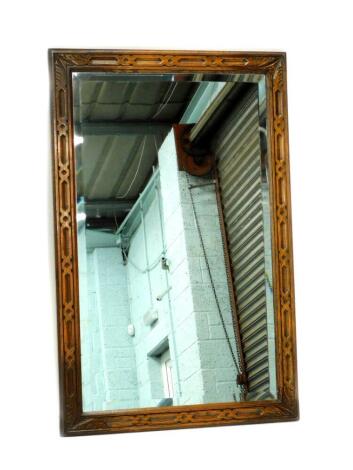 A carved oak wall mirror, with a rectangular bevelled plate, 104cm x 67cm.