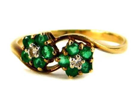 A 9ct gold dress ring, set with two flower designs, each with emerald and tiny diamond, on twist decoration, ring size O½, 1.7g all in.