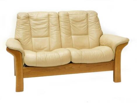 A cream leather Stressless two seater sofa, with beech frame, 102cm wide. (AF)