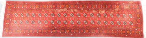 An Afghan Turkoman type runner, with two rows of medallions, on a red ground with multiple borders, 84cm x 192cm.