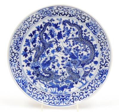 A Chinese blue and white plate, decorated with a pair of four clawed dragons chasing the flaming pearl among peonies, the outer border of stylized peonies, marked Wang beneath, 20cm diameter.