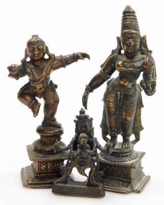 An Indian Hindu bronze figure of Krishna, modelled standing on one leg holding a ball of butter, 8.5cm high, bronze figure of Parvati, modelled standing holding a lotus flower, raised on a square base, 10cm high, and a further figure of a deity, possibly