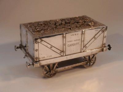 An Edwardian silver table cigarette box in the form of a railway coal truck