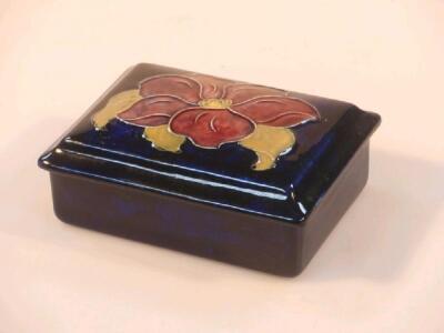 A Moorcroft rectangular box and cover with flower head decoration on a blue ground