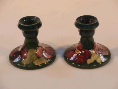 A pair of Moorcroft dwarf candlesticks with flower decoration on a green ground