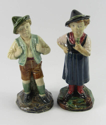 A pair of Bernard Bloch figural majolica spill vases, late 19thC, modelled as a boy and girl in Alpine costume, raised on naturalistic bases, impressed marks, 22cm high.