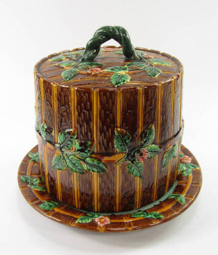 A majolica stilton dish and cover, of barrel form and moulded as a barrel bound with bands of flowers and leaves, 28cm x 32cm.