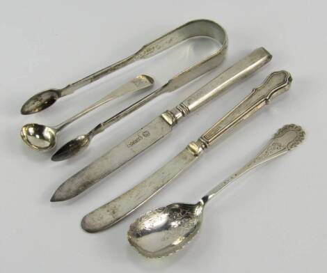 Silver flatware, including a pair of George IV sugar tongs, London 1826, George III salt spoon, crest engraved, jam spoon, Sheffield 1922, 1.54t oz, and two silver handled knives.