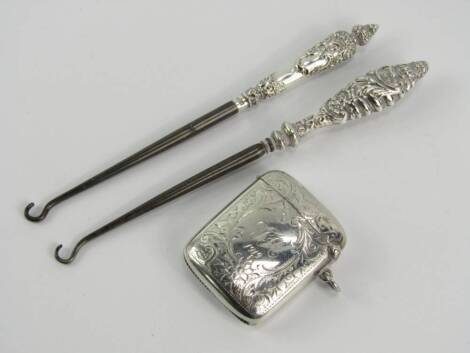 A silver curvilinear vesta case, with foliate engraving, reserve monogram and date engraved, hallmarked Birmingham and two Victorian button hooks, with embossed silver handles, Birmingham 1899 and 1900.