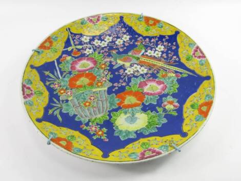 A Japanese enamel charger, early 20thC, decorated with peacocks, basket of flowers and prunus blossom against a blue ground, 46cm diameter.