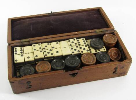 A mahogany box, containing bone and ebony dominoes, further set of dominoes and a quantity of draught counters.