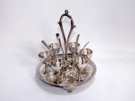 A Victorian plated egg cruet, of circular form with engraved fern decoration, holding six egg cups and spoons, raised on three scroll feet, 24cm x 21cm.