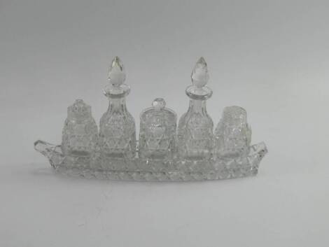 A cut crystal five bottle cruet, seated in a boat shaped stand, 30cm long.