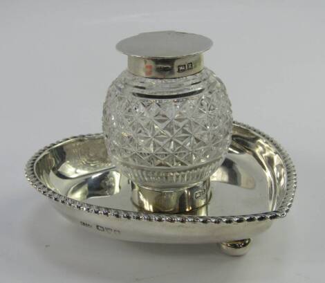 A Victorian cut glass and silver inkwell, on a heart shaped stand with gadrooned rim, raised on three bun feet, Stokes & Ireland Ltd, Chester 1900, stand 2.82t oz.