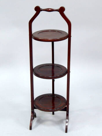 An Edwardian mahogany three tier folding cake stand, with boxwood line inlay, raised on curved legs, 88cm high.