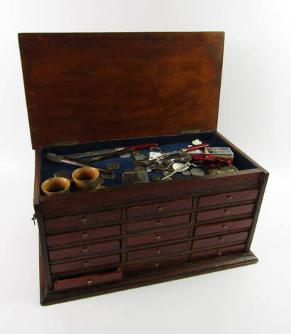 A mahogany collector's chest, of rectangular section with a lidded sectional top above an arrangement of fifteen drawers, raised on a plinth base, with various collectables, 45.5cm x 25.5cm x 23cm.