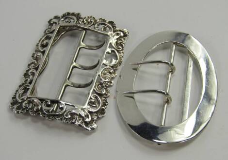 An Edwardian oval silver belt buckle by Mappin & Webb, London 1910, 0.63t oz, and a 19thC French white metal belt buckle of rectangular form embossed with rococo shells, (2).